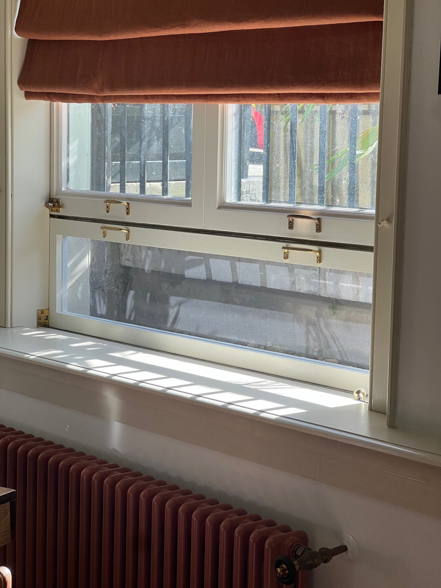 Houten hor geplaatst in een blauw geschilderd Amsterdams schuifraam met uitzicht op de gracht